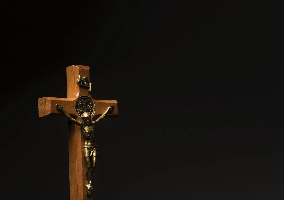 Crucifijo de madera con figura en bronce, sobre fondo oscuro